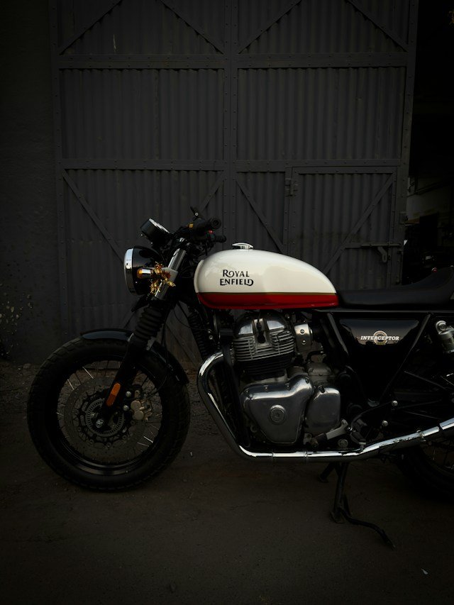 Royal Enfield motorcycle beside workshop doors, archive cover reference
